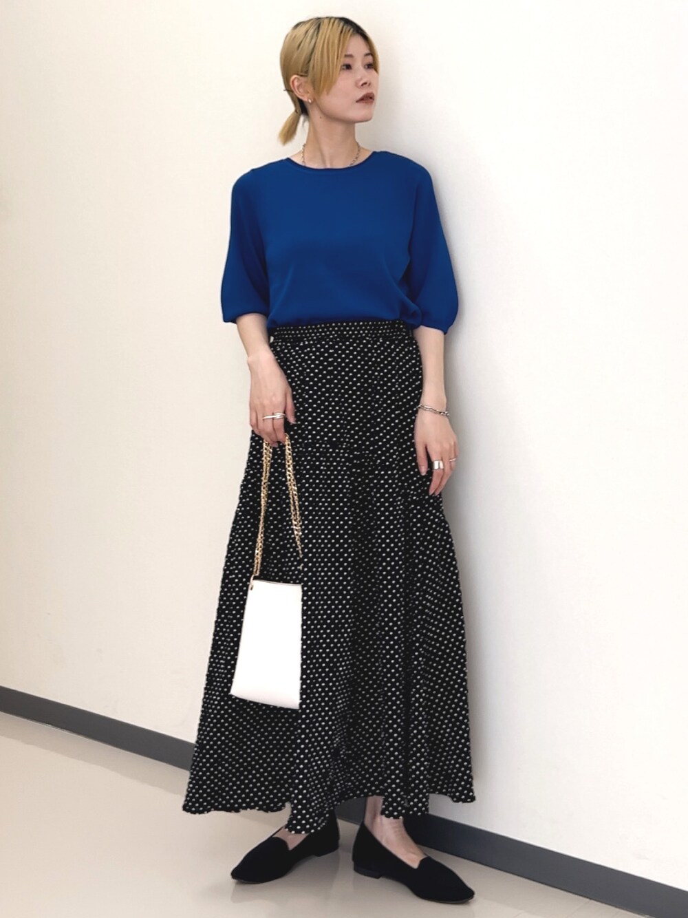 ブラック系のスカート、ブラック系のパンプス、ブルー系のニット/セーターを着用したレディースの夏コーディネートの1枚目の写真