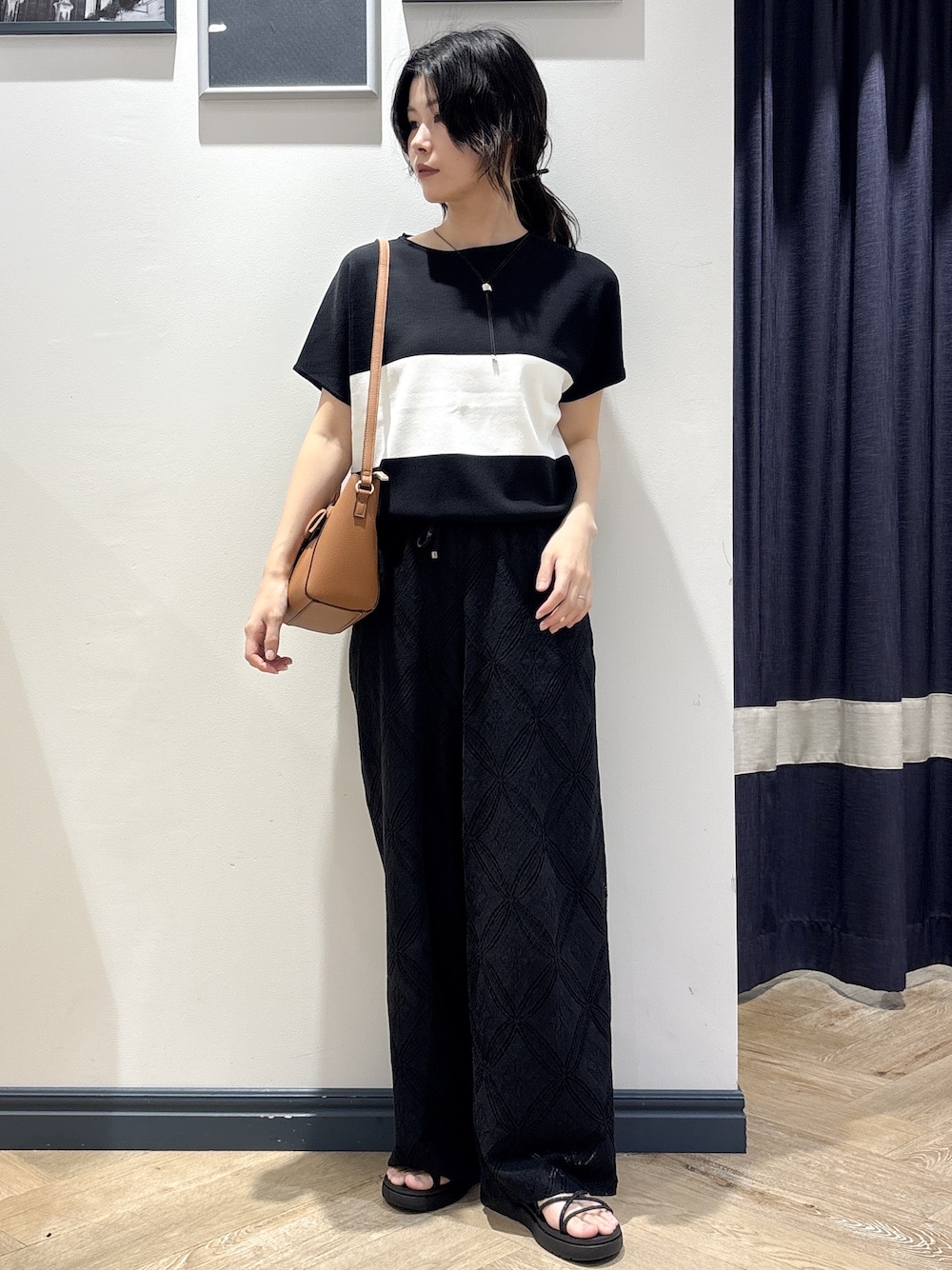 ブラック系のニット/セーター、ブラック系のその他パンツ、イエロー系のショルダーバッグを着用したレディースの春コーディネートの1枚目の写真