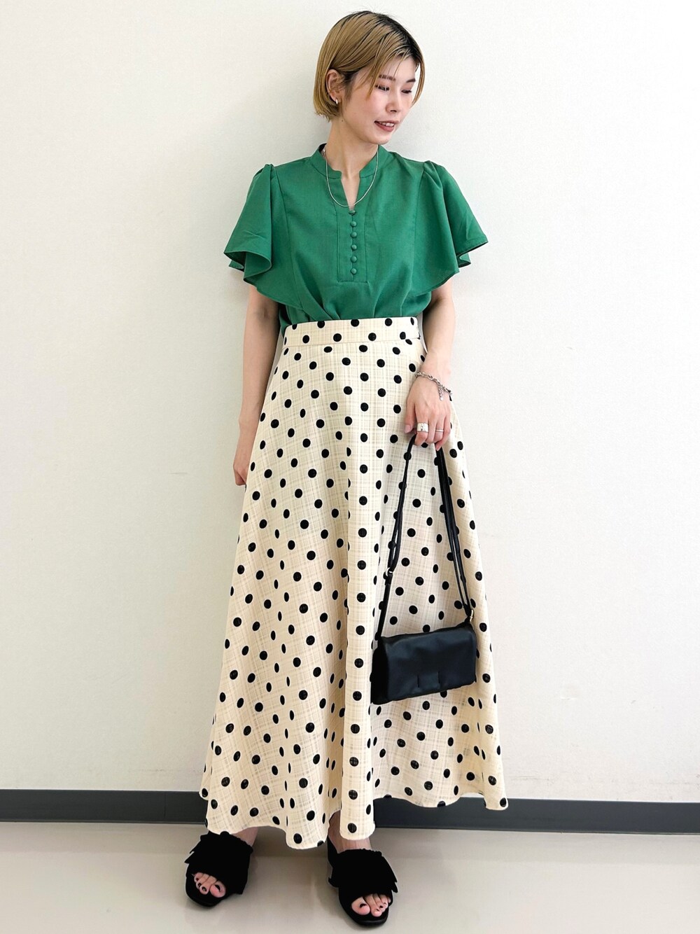 ベージュ系のスカート、グリーン系のシャツ/ブラウス、ブラック系のショルダーバッグを着用したレディースの夏コーディネートの1枚目の写真