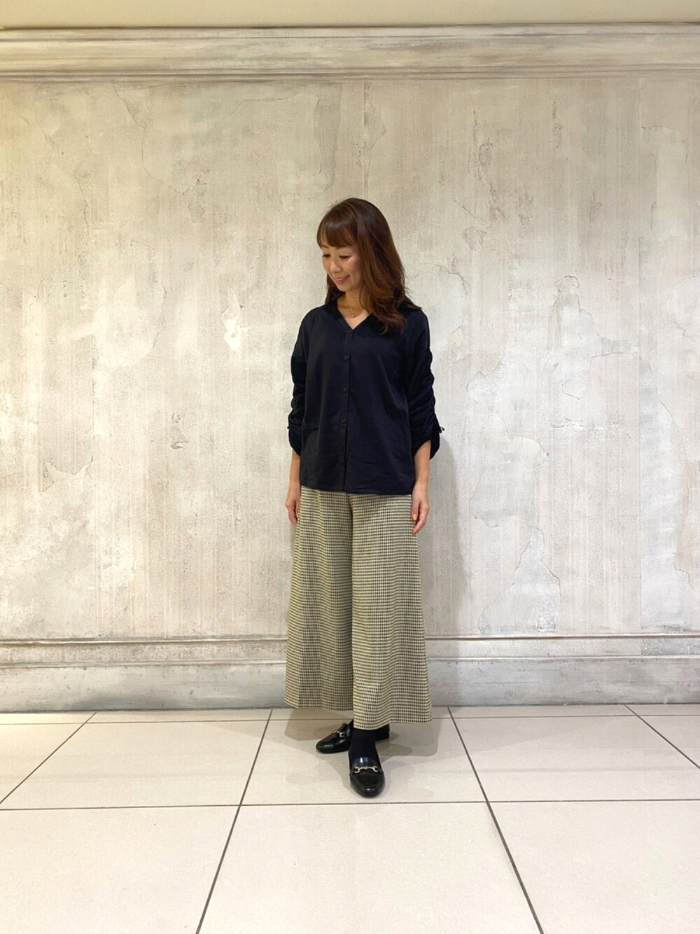 ベージュ系のパンツ、ブラック系のシャツ/ブラウスを着用したレディースの秋コーディネートの1枚目の写真