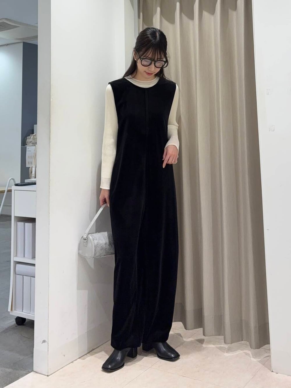 ブラック系のブーツ、ベージュ系のニット/セーター、グレー系のハンドバッグを着用したレディースの冬コーディネートの1枚目の写真