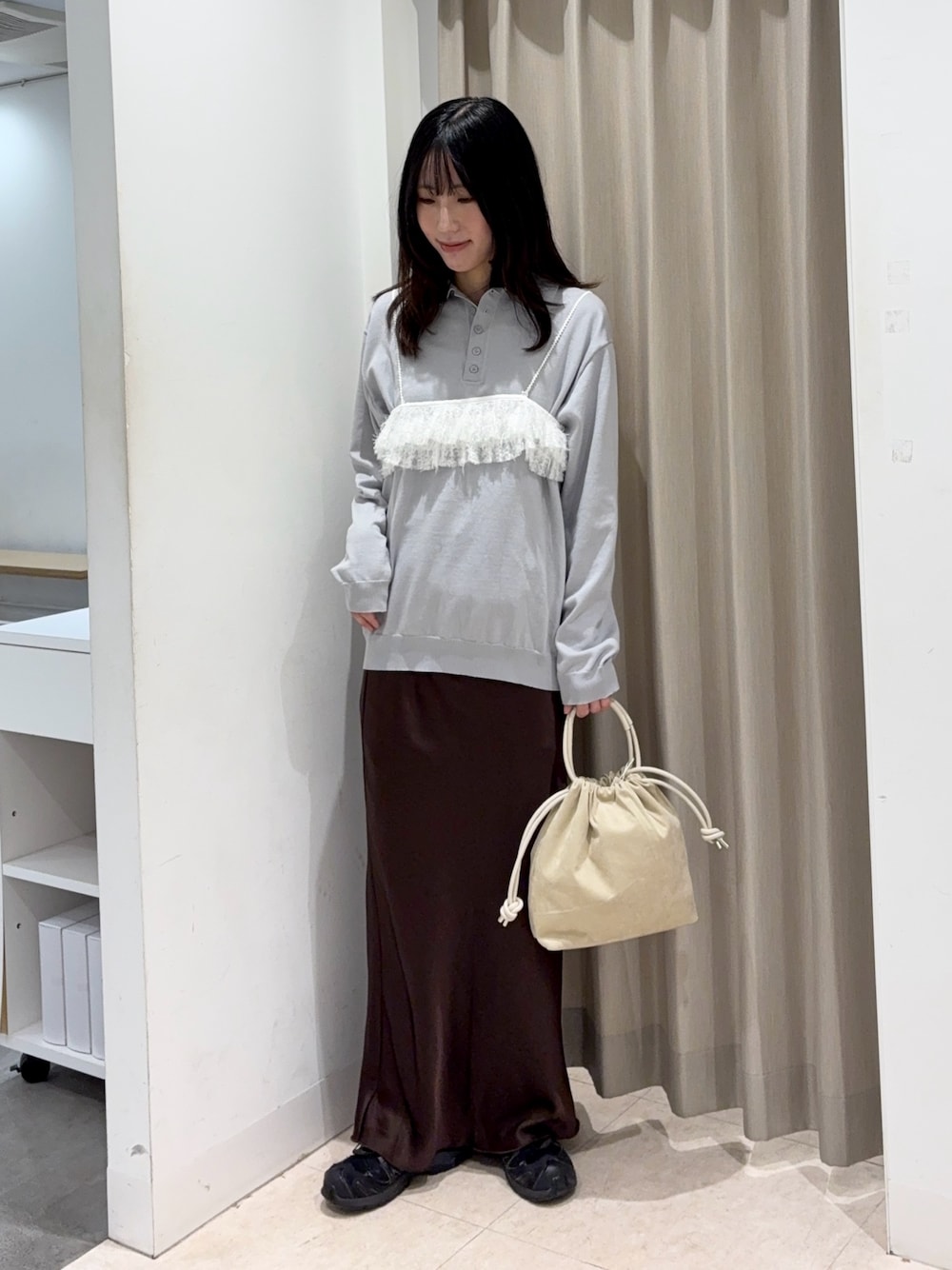 グレー系のニット/セーター、ベージュ系のハンドバッグ、ブラウン系のスカートを着用したレディースの春コーディネートの1枚目の写真