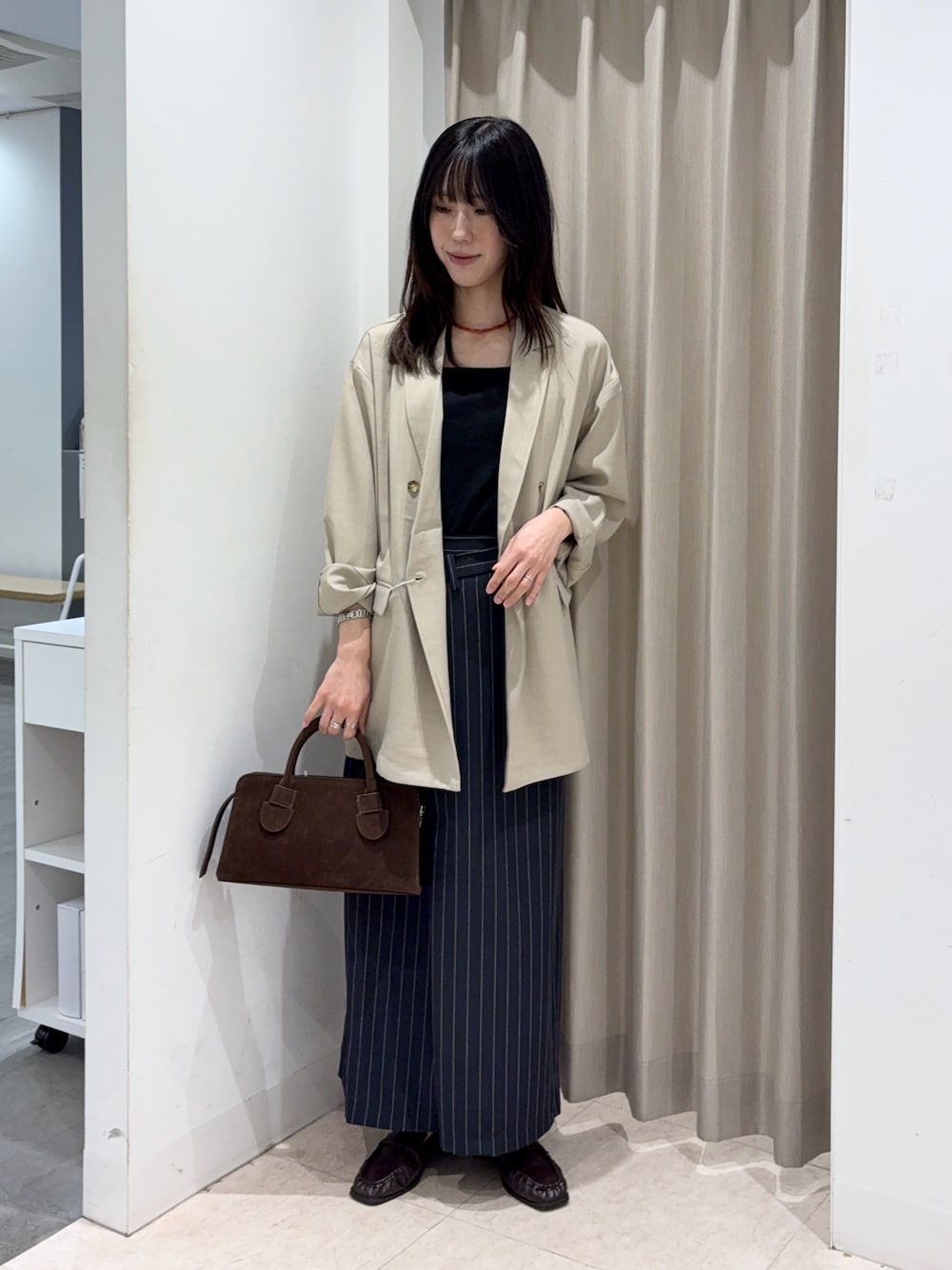 ブラック系のキャミソール、ベージュ系のその他アウター、ブラウン系のボストンバッグを着用したレディースの春コーディネートの1枚目の写真