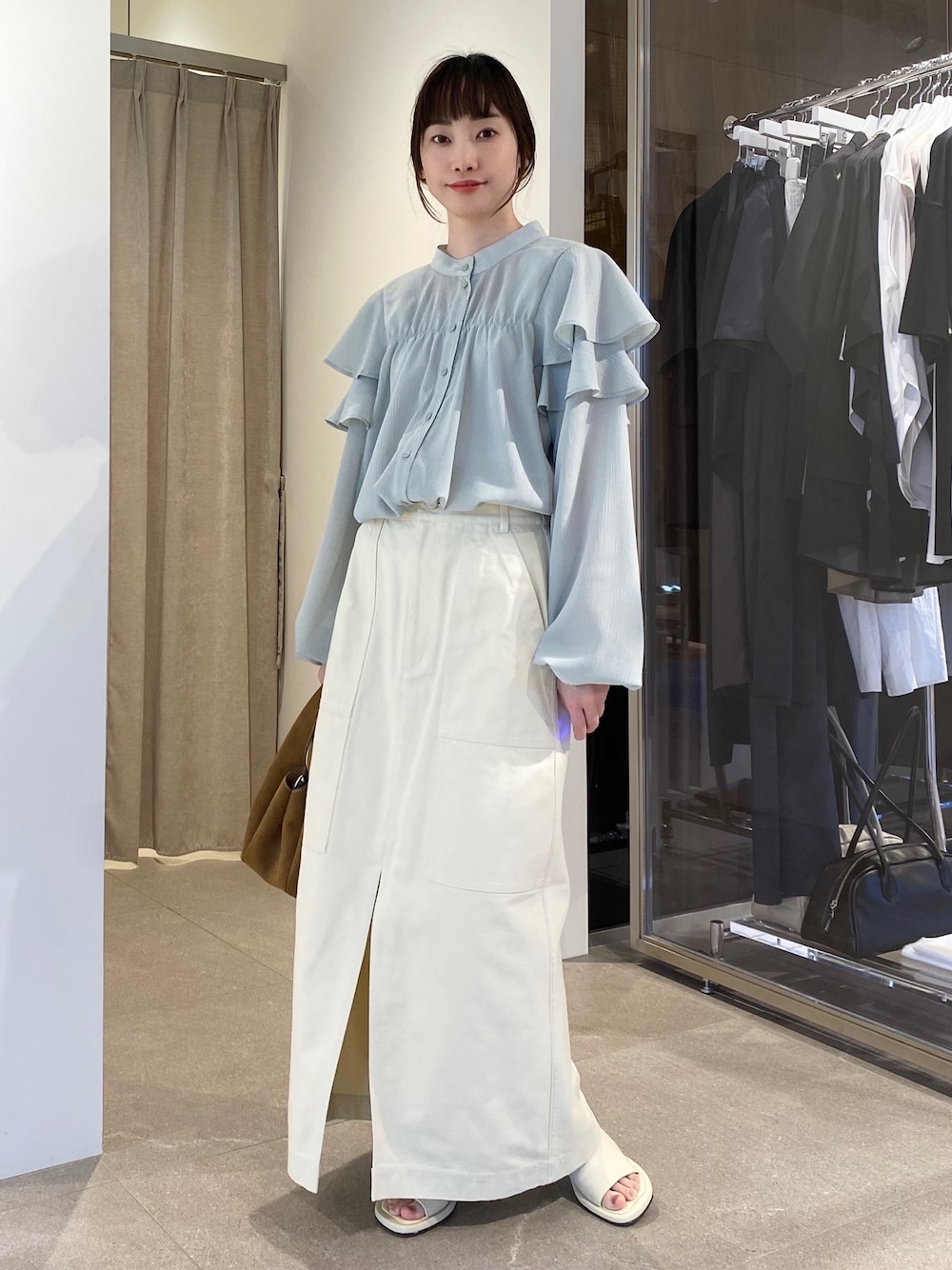 ブルー系のシャツ/ブラウス、ベージュ系のスカート、ブラウン系のトートバッグを着用したレディースの冬コーディネートの1枚目の写真