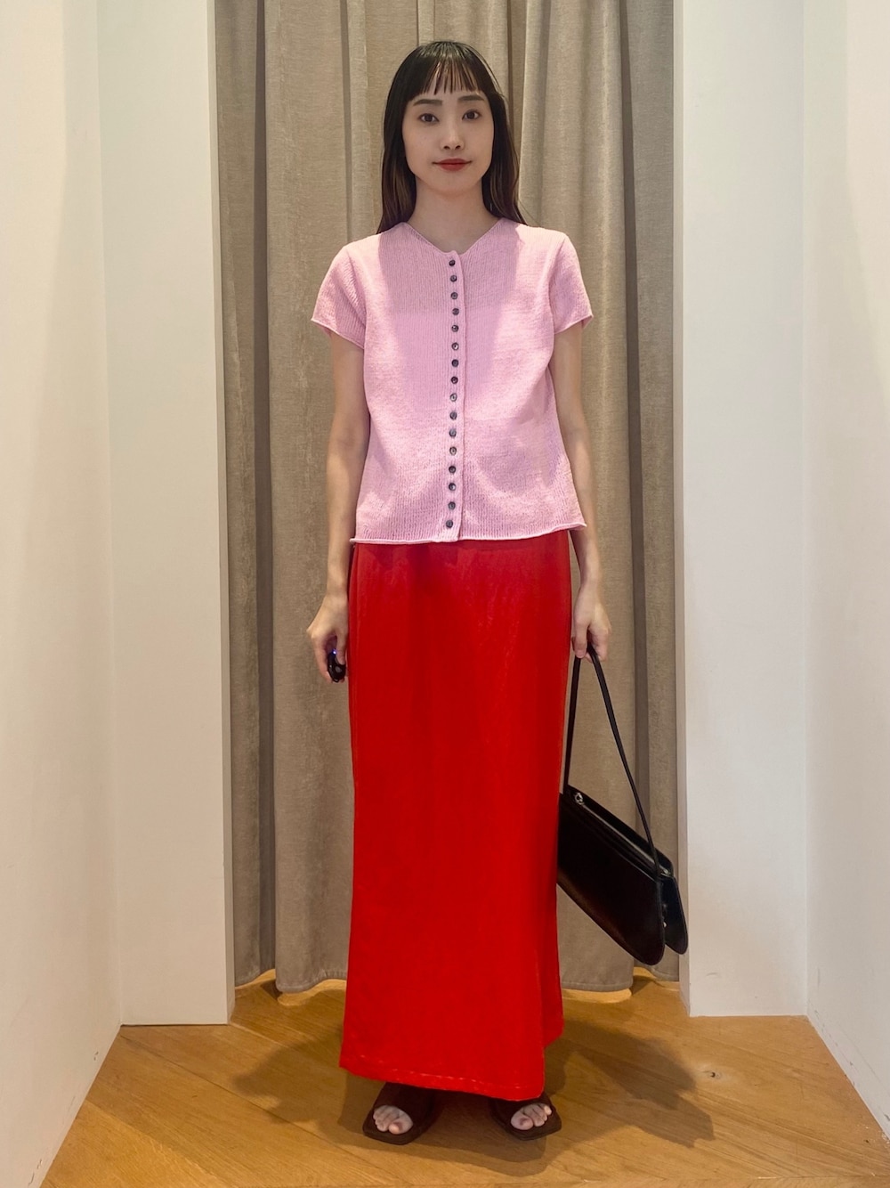 レッド系のスカート、ピンク系のニット/セーター、ブラウン系のサンダルを着用したレディースの春コーディネートの1枚目の写真