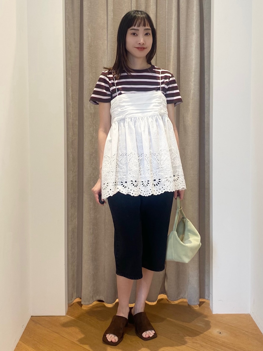 レッド系のTシャツ/カットソー、グリーン系のショルダーバッグ、ブラウン系のサンダルを着用したレディースの春コーディネートの1枚目の写真