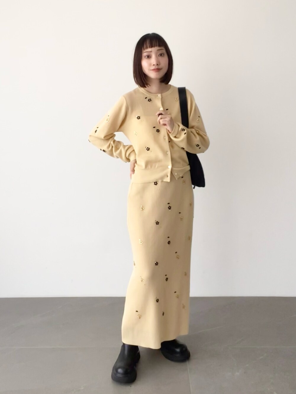 ベージュ系のスカート、ベージュ系のカーディガン/ボレロ、ブラック系のショルダーバッグを着用したレディースの夏コーディネートの1枚目の写真