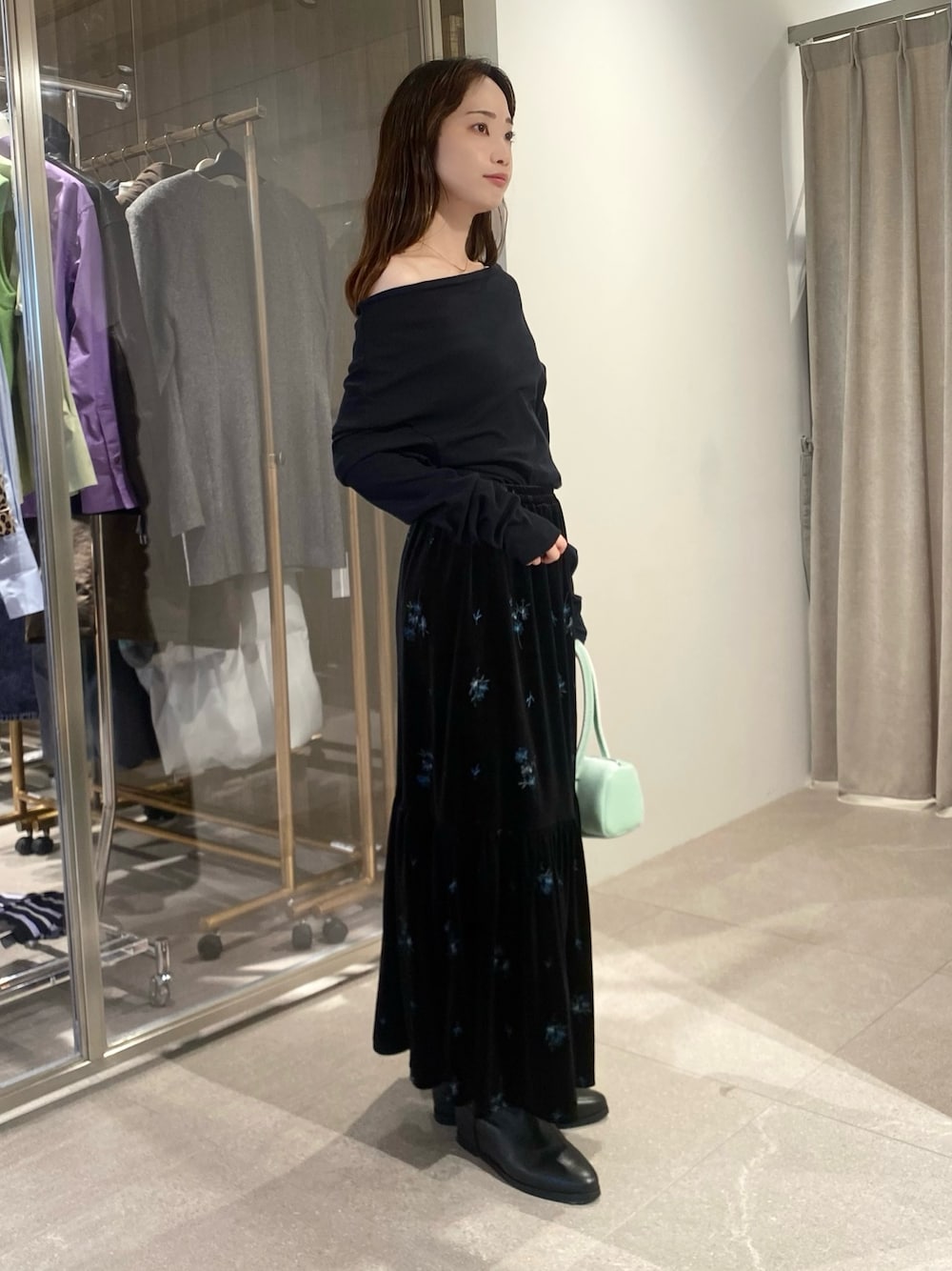 ブラック系のスカート、ブラック系のTシャツ/カットソー、グリーン系のハンドバッグを着用したレディースの秋コーディネートの1枚目の写真