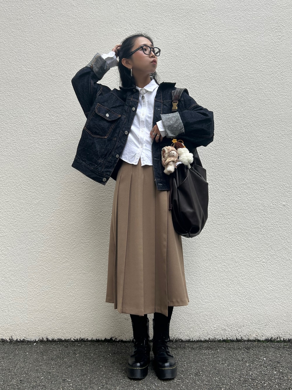 ベージュ系のスカート、ブラウン系のショルダーバッグ、ブルー系のデニムジャケットを着用したレディースの秋コーディネートの1枚目の写真