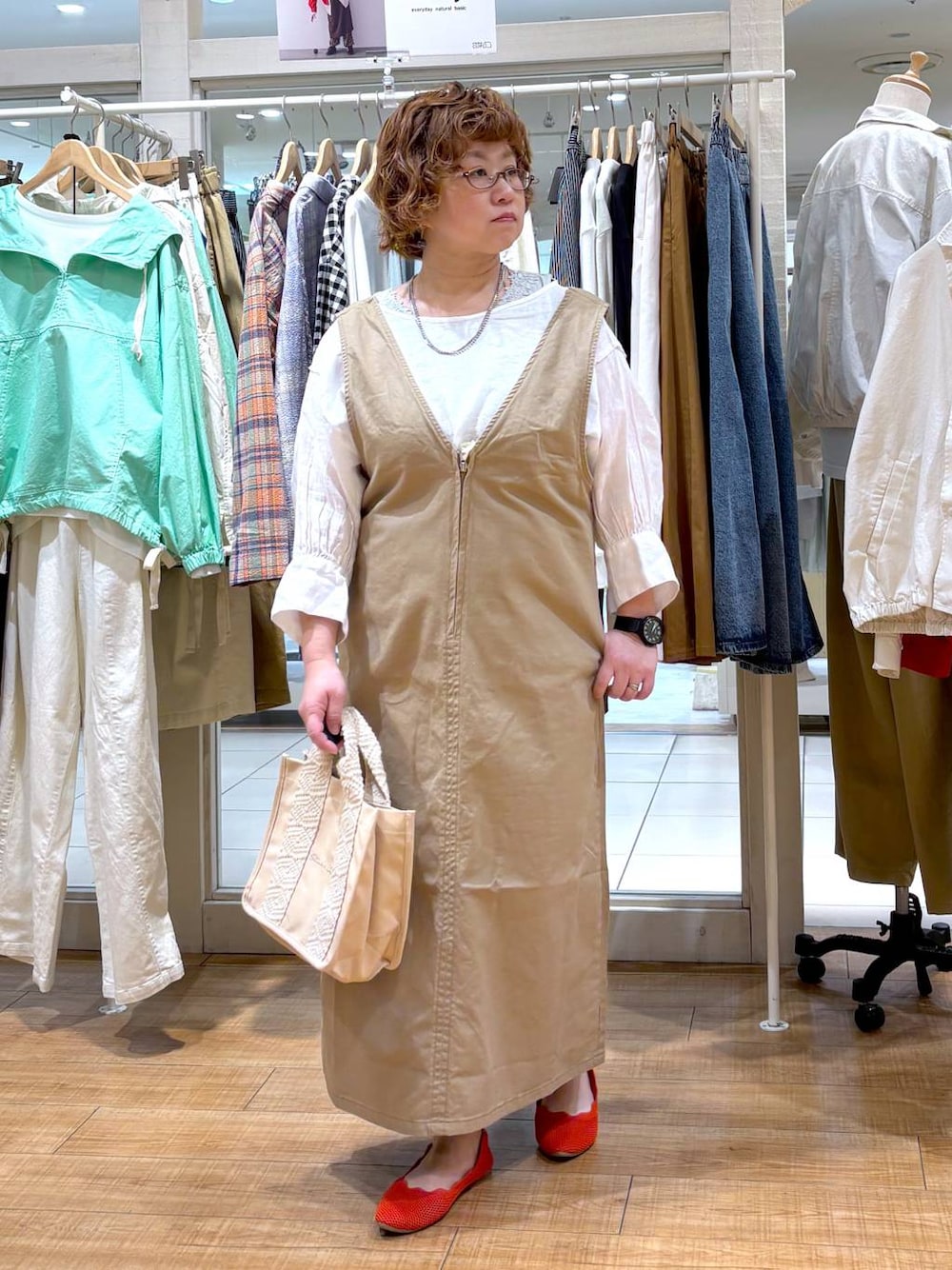 ベージュ系のジャンパースカート、ホワイト系のシャツ/ブラウス、グリーン系のタンクトップを着用したレディースの春コーディネートの1枚目の写真