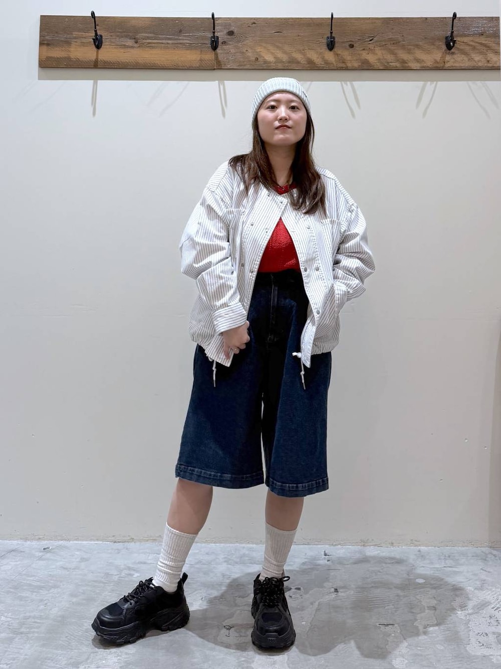 ブラック系のスニーカー、ベージュ系のカバーオール、レッド系のTシャツ/カットソーを着用したレディースの春コーディネートの1枚目の写真