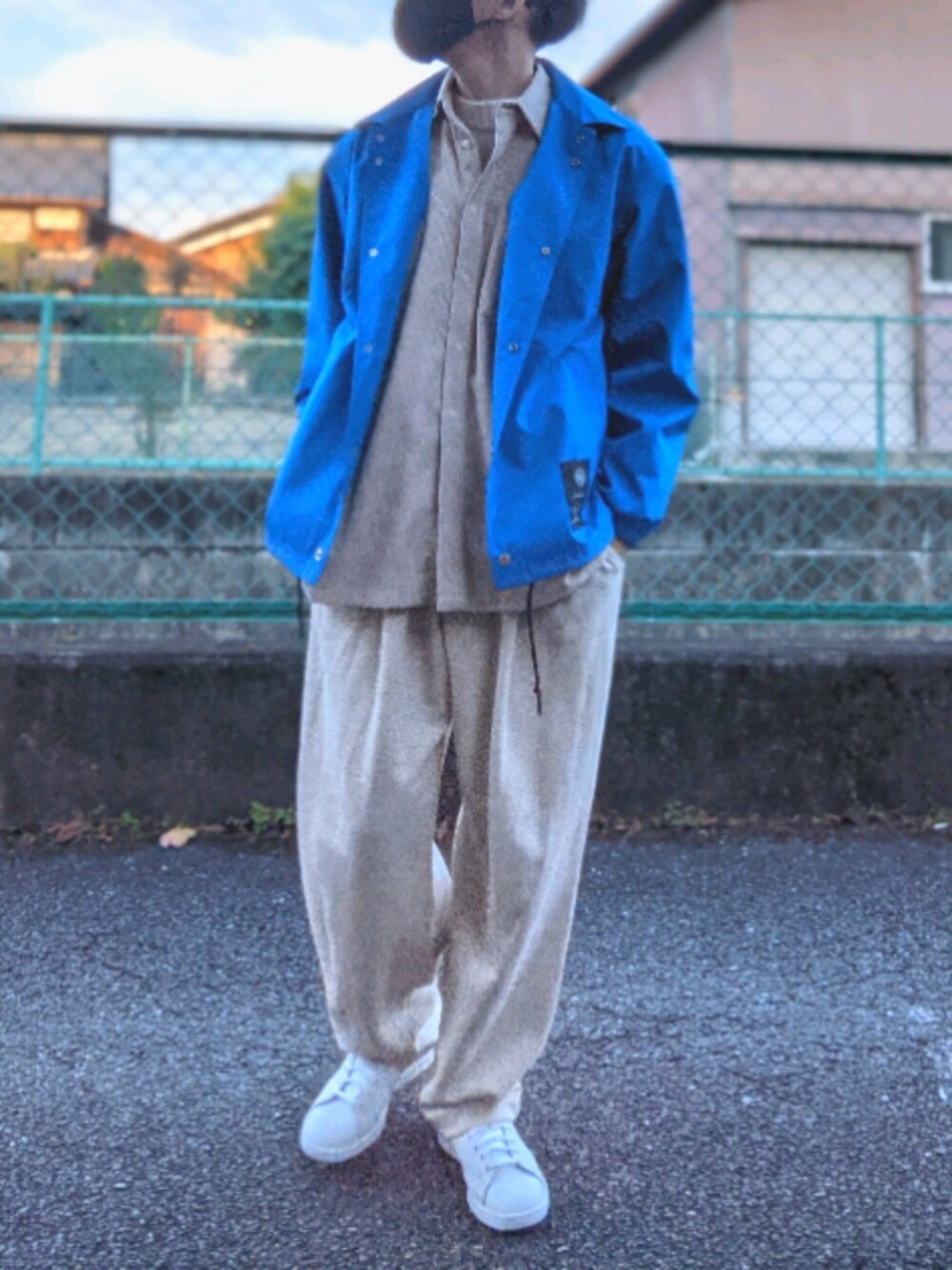 ホワイト系のスニーカー、ベージュ系のスウェットパンツ、ブルー系のナイロンジャケットを着用したメンズの秋コーディネートの1枚目の写真