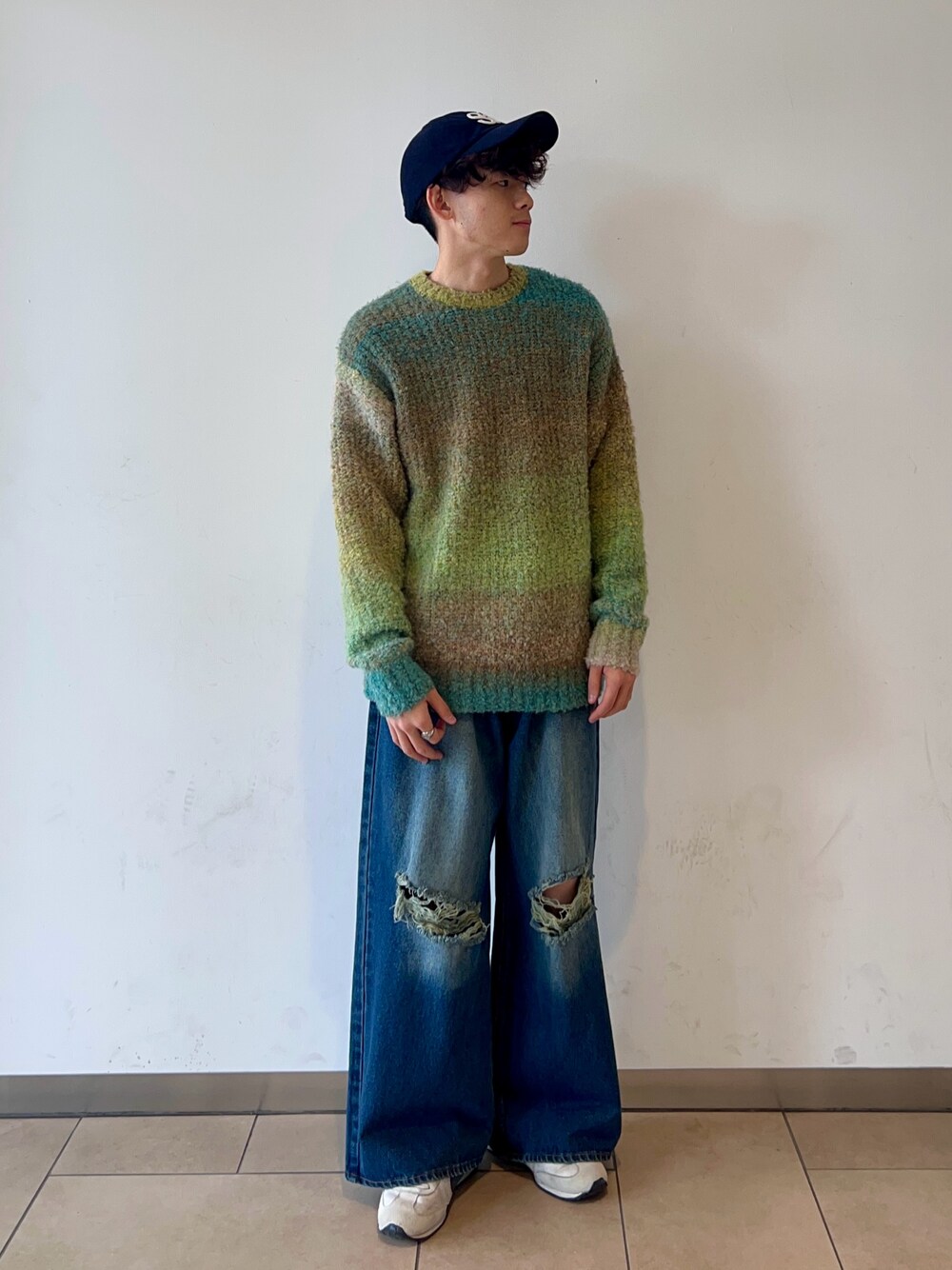 グリーン系のニット/セーター、ブルー系のデニムパンツ、ブルー系のキャップを着用したメンズの冬コーディネートの1枚目の写真