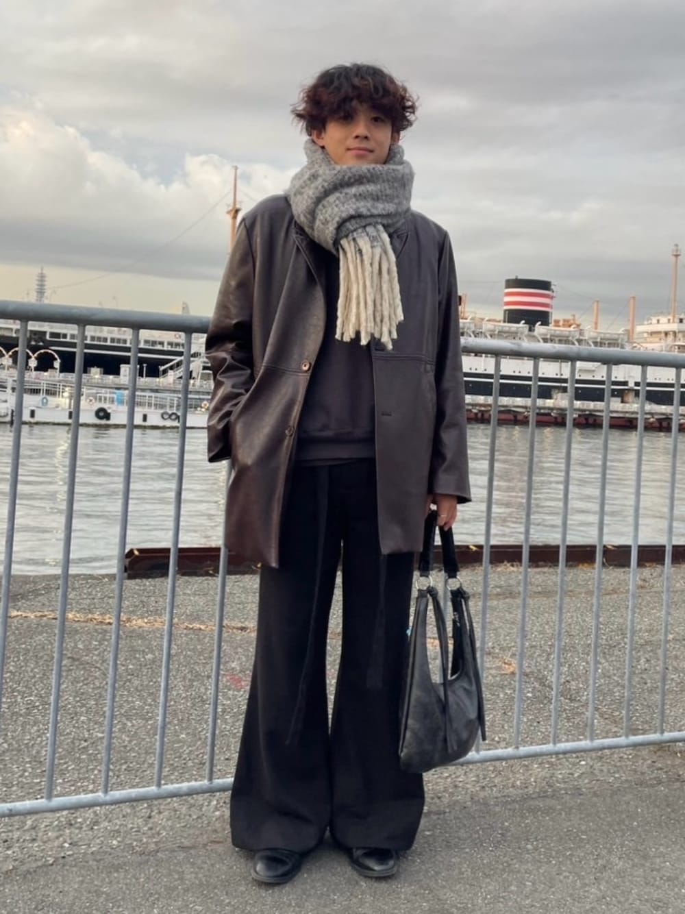 ブラック系のハンドバッグ、ブラック系のその他パンツ、ブラック系のブーツを着用したメンズの冬コーディネートの1枚目の写真