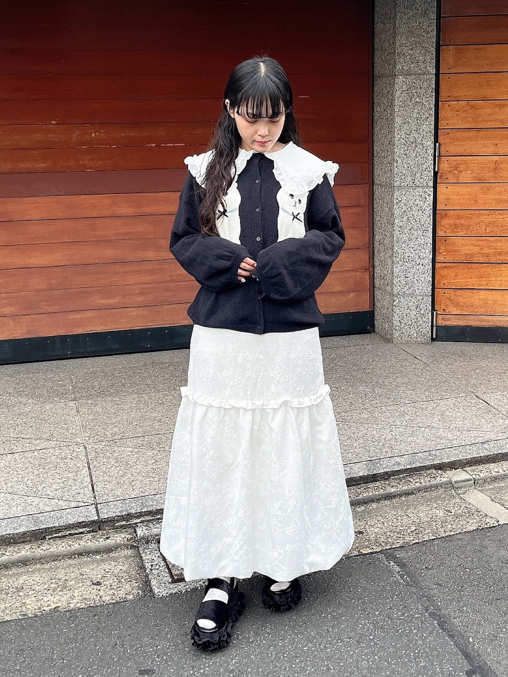 ホワイト系のスカート、ブラック系のカーディガン/ボレロ、ホワイト系のシャツ/ブラウスを着用したレディースの秋コーディネートの1枚目の写真