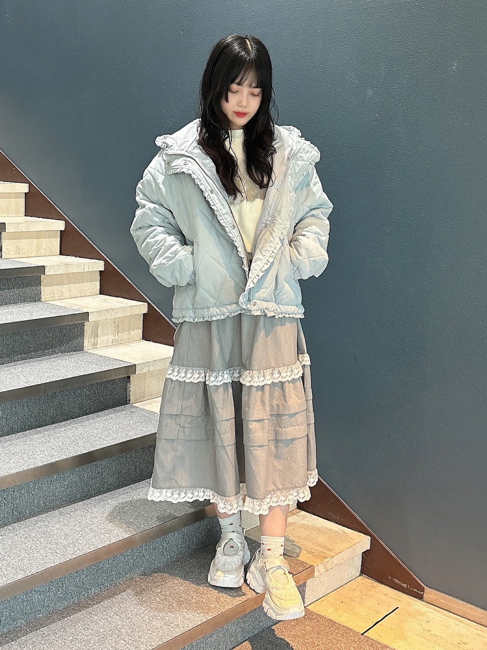 ブルー系のダウンジャケット/コート、ホワイト系のニット/セーター、グレー系のスカートを着用したレディースの秋コーディネートの1枚目の写真