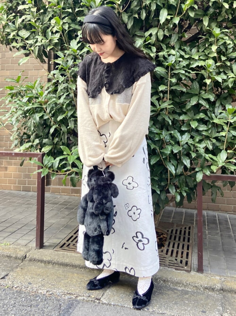 ブラック系のハンドバッグ、ホワイト系のカーディガン/ボレロ、ホワイト系のスカートを着用したレディースの秋コーディネートの1枚目の写真