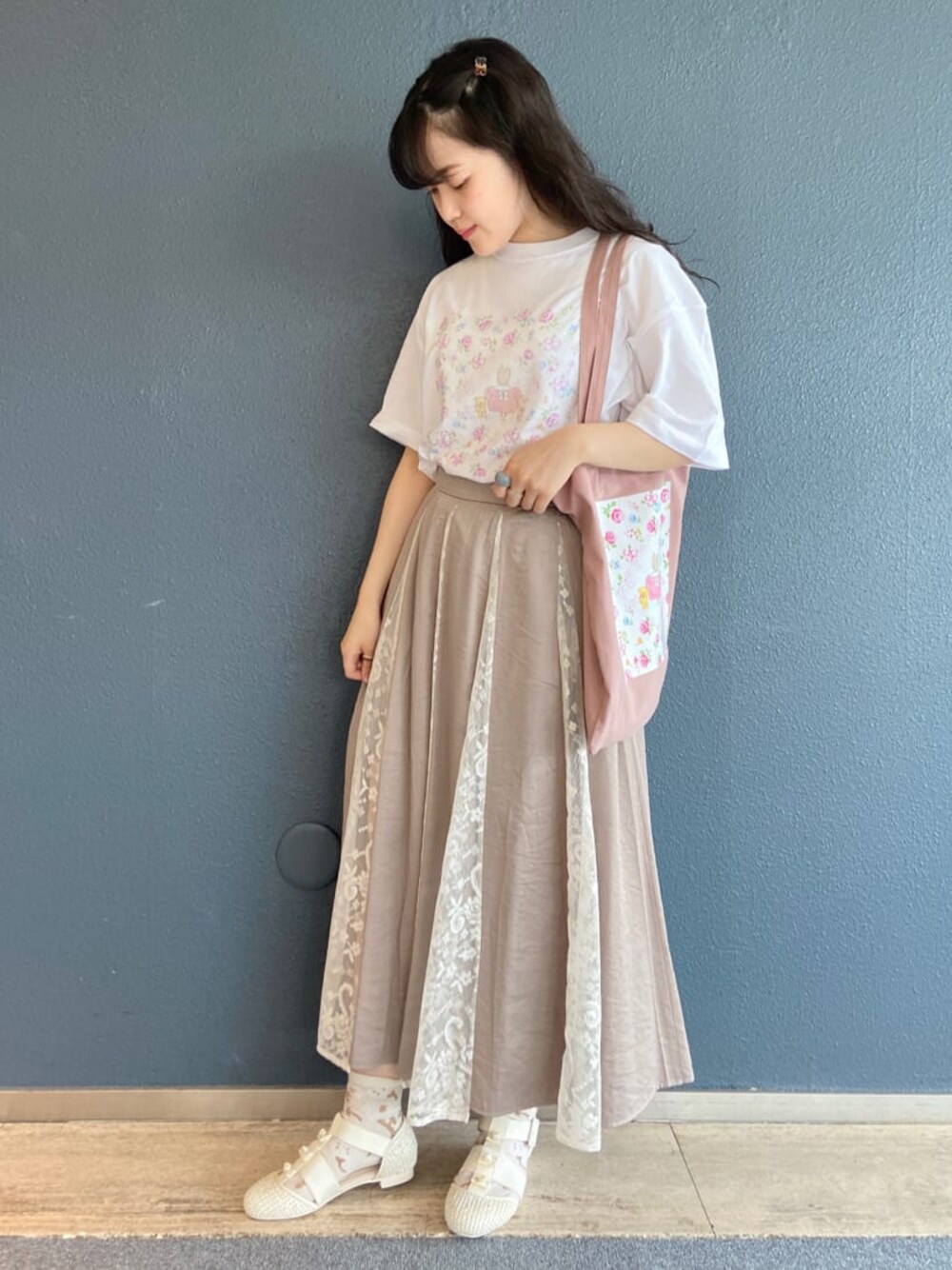 ベージュ系のスカート、ホワイト系のパンプス、ホワイト系のトートバッグを着用したレディースの夏コーディネートの1枚目の写真
