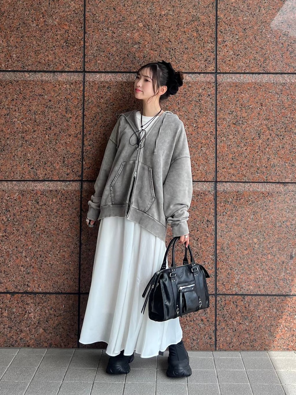 グレー系のパーカー、ブラック系のボストンバッグ、ブラック系のブーツを着用したレディースの夏コーディネートの1枚目の写真