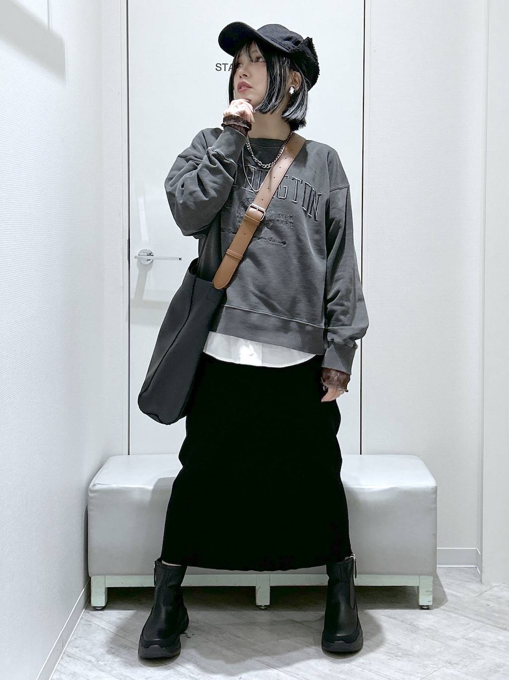 ブラック系のショルダーバッグ、ブラック系のブーツ、ブラック系のスカートを着用したレディースの秋コーディネートの1枚目の写真