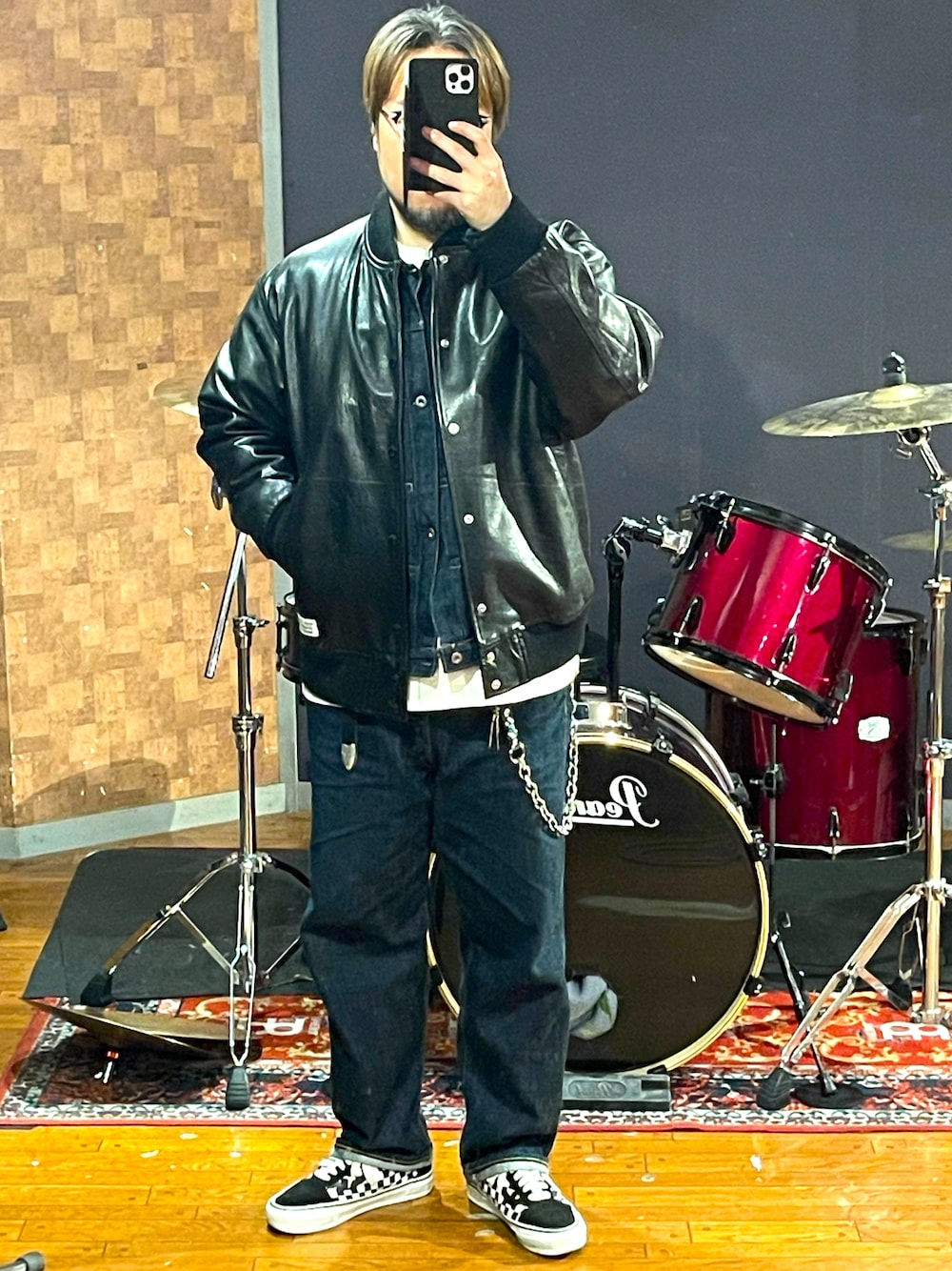 ブラック系のスタジャン、ブルー系のデニムパンツ、ホワイト系のスニーカーを着用したメンズの秋コーディネートの1枚目の写真