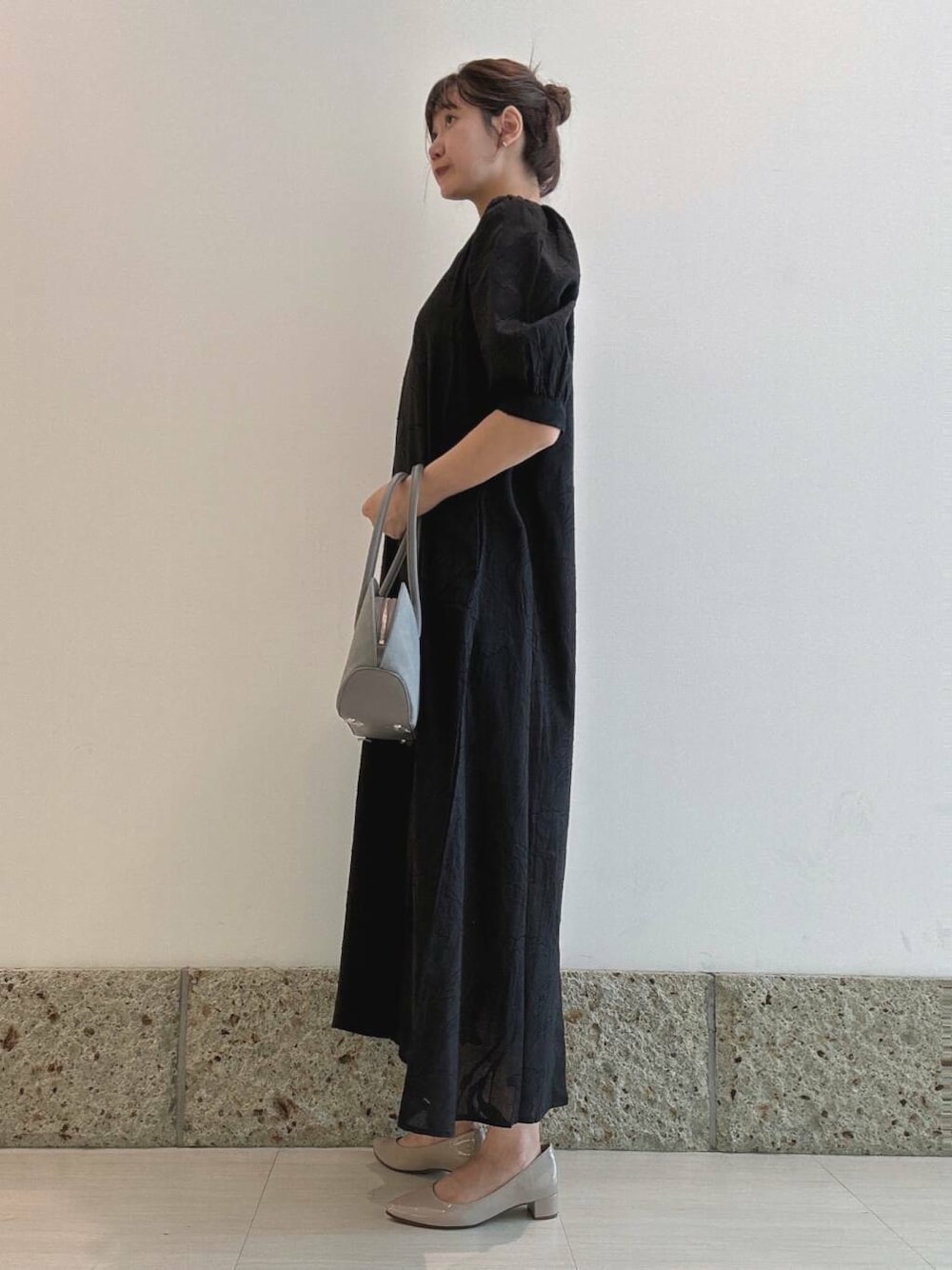 ベージュ系のパンプス、ブルー系のハンドバッグ、ブラック系のワンピースを着用したレディースの秋コーディネートの1枚目の写真