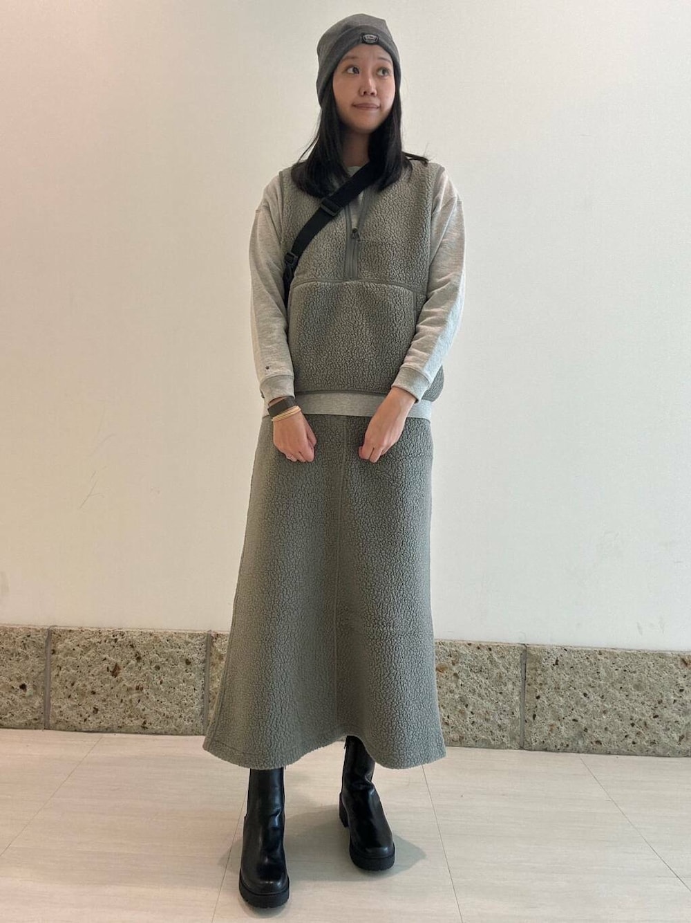 ブラック系のブーツ、ブラック系のショルダーバッグ、グレー系のベストを着用したレディースの秋コーディネートの1枚目の写真