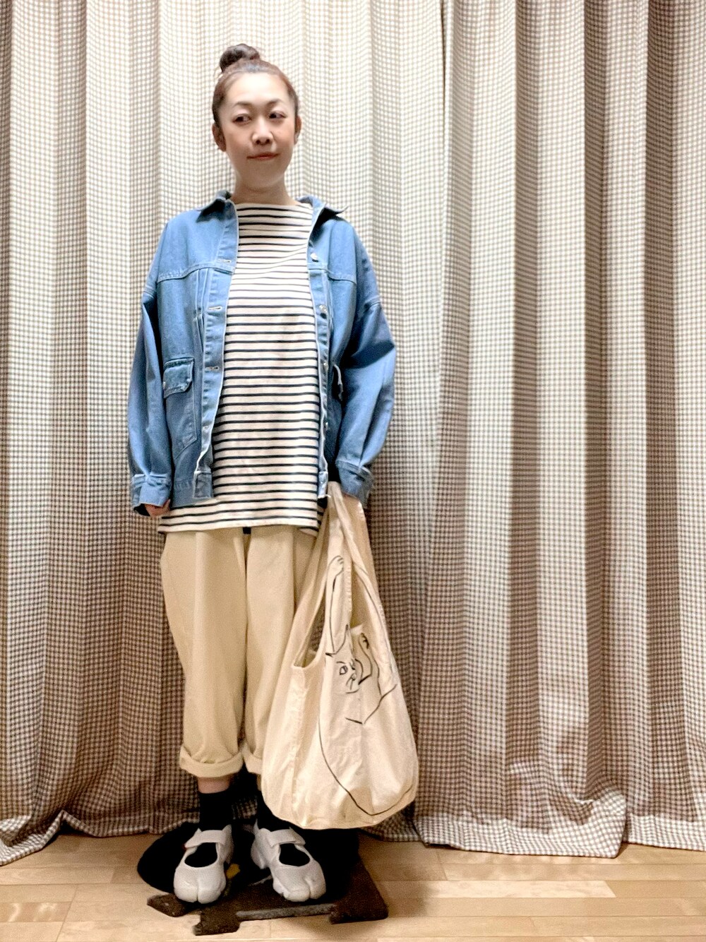 ブルー系のデニムジャケット、ブルー系のチュニック、ベージュ系のパンツを着用したレディースの春コーディネートの1枚目の写真