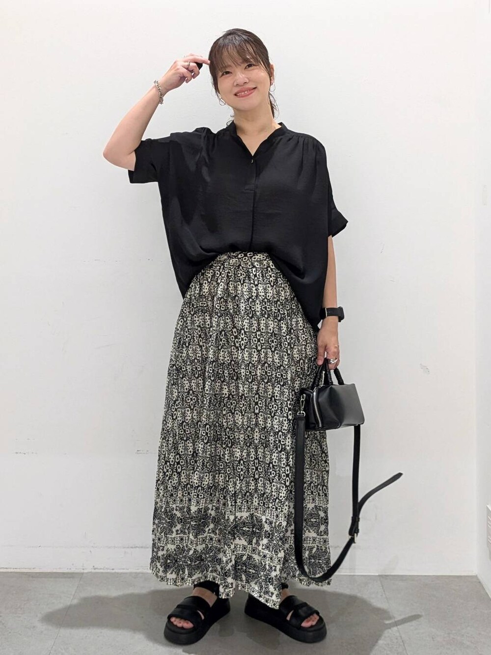 ブラック系のスカート、ブラック系のサンダル、ブラック系のTシャツ/カットソーを着用したレディースの夏コーディネートの1枚目の写真