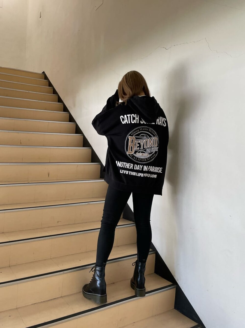 グレー系のパーカー、ブラック系のブーツ、ホワイト系のTシャツ/カットソーを着用したレディースの冬コーディネートの1枚目の写真