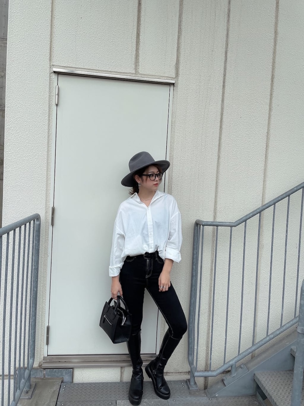 ブラック系のハンドバッグ、ブラック系のデニムパンツ、ホワイト系のシャツ/ブラウスを着用したレディースの秋コーディネートの1枚目の写真