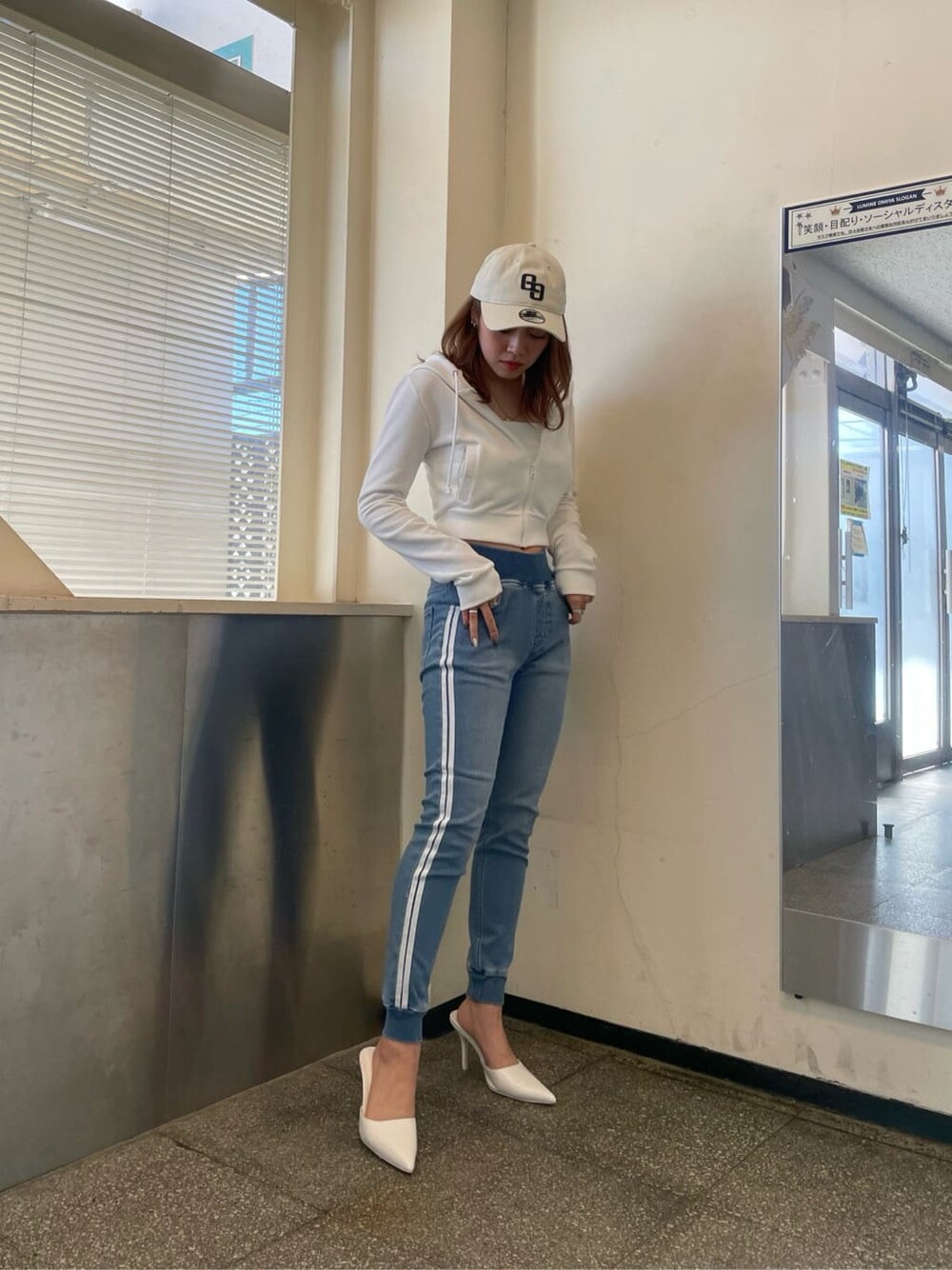 ホワイト系のパーカー、ホワイト系のパンプス、ブルー系のデニムパンツを着用したレディースの冬コーディネートの1枚目の写真