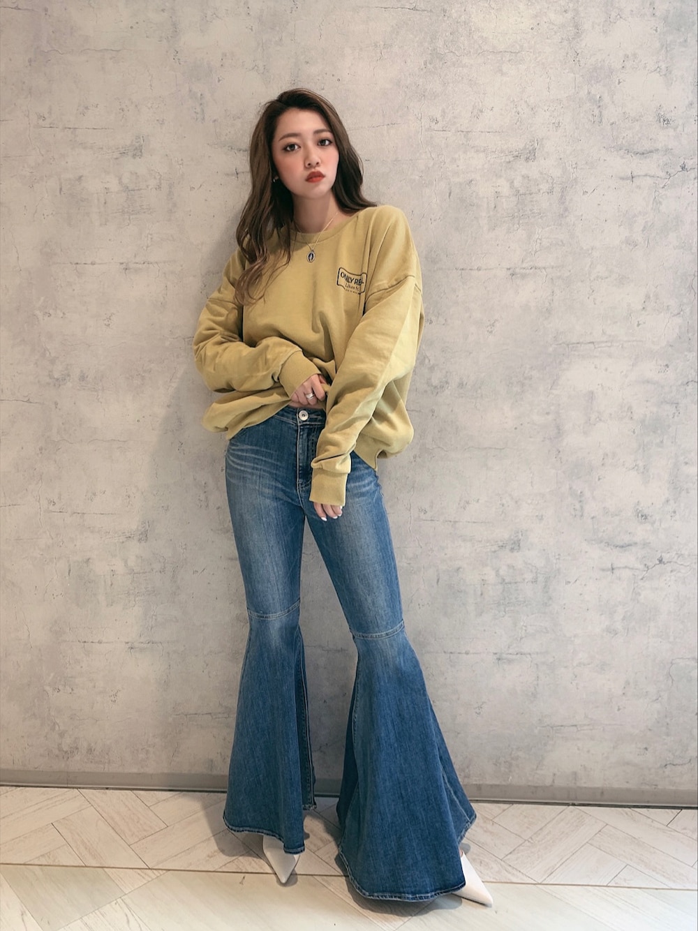 ホワイト系のパンプス、ブルー系のデニムパンツ、イエロー系のスウェットを着用したレディースの冬コーディネートの1枚目の写真