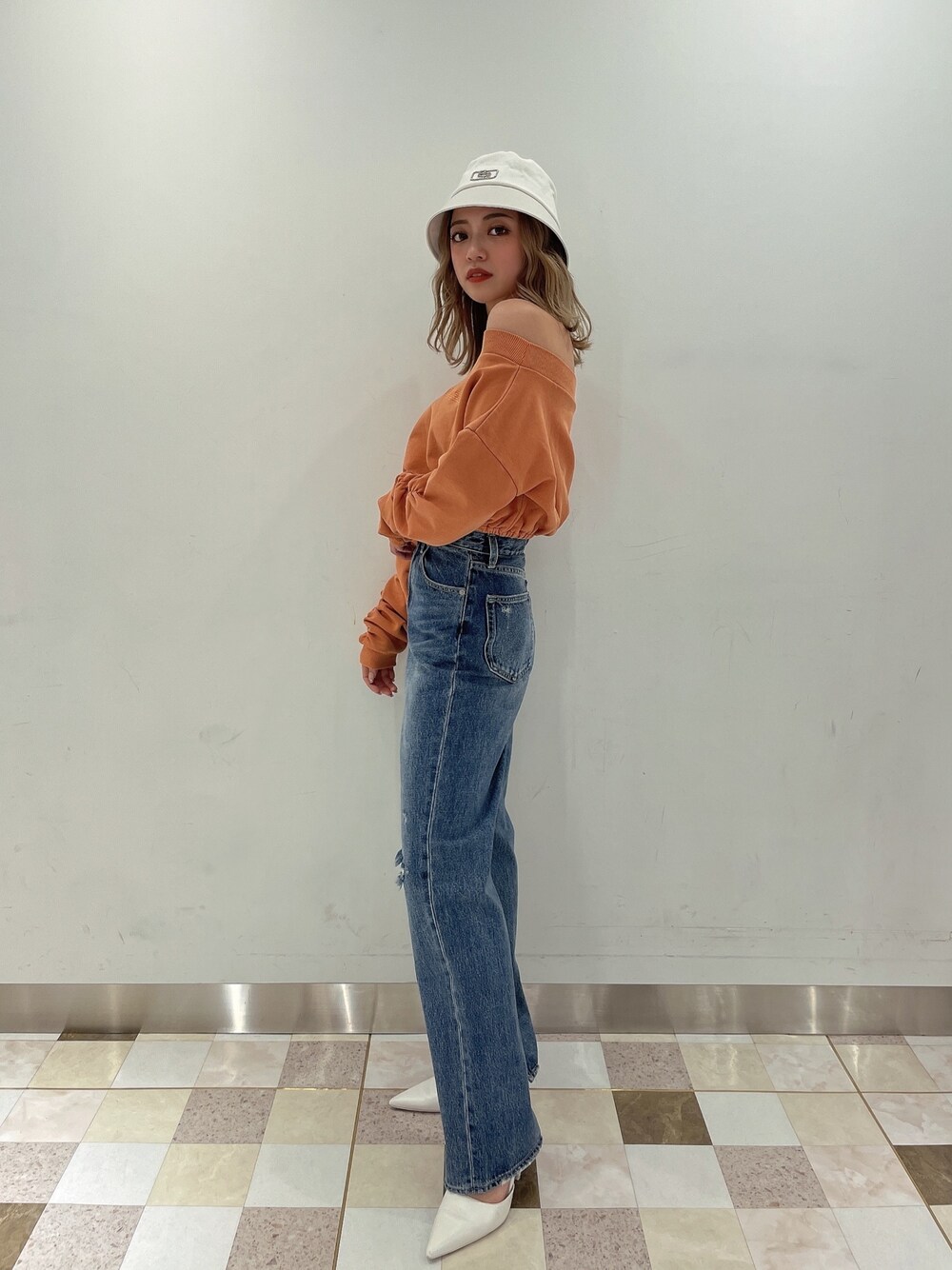 オレンジ系のTシャツ/カットソー、ブルー系のデニムパンツ、ホワイト系のパンプスを着用したレディースの冬コーディネートの1枚目の写真