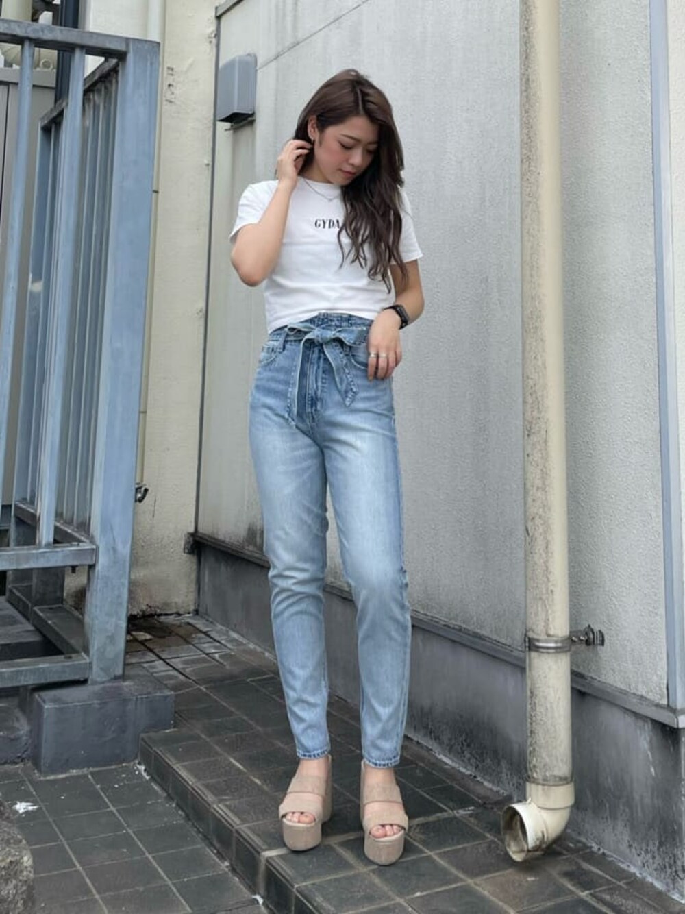 ホワイト系のサンダル、ホワイト系のTシャツ/カットソー、ブルー系のデニムパンツを着用したレディースの春コーディネートの1枚目の写真