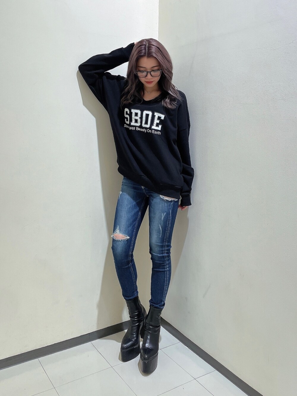 ブラック系のスウェット、ブルー系のデニムパンツ、ブラック系のブーツを着用したレディースの秋コーディネートの1枚目の写真