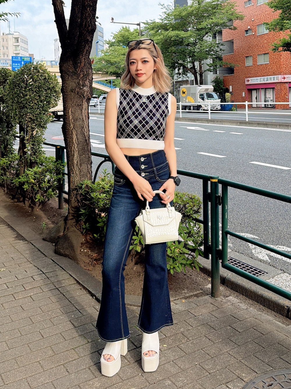 ブラック系のニット/セーター、ブルー系のデニムパンツ、ホワイト系のハンドバッグを着用したレディースの夏コーディネートの1枚目の写真