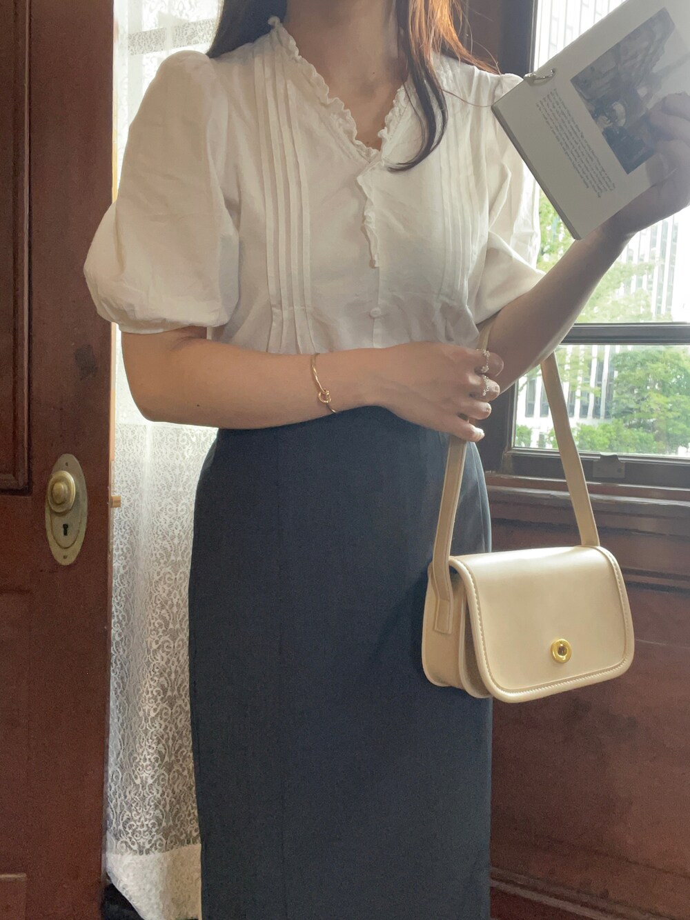 ブラック系のスカート、ホワイト系のシャツ/ブラウス、ベージュ系のショルダーバッグを着用したレディースの夏コーディネートの1枚目の写真