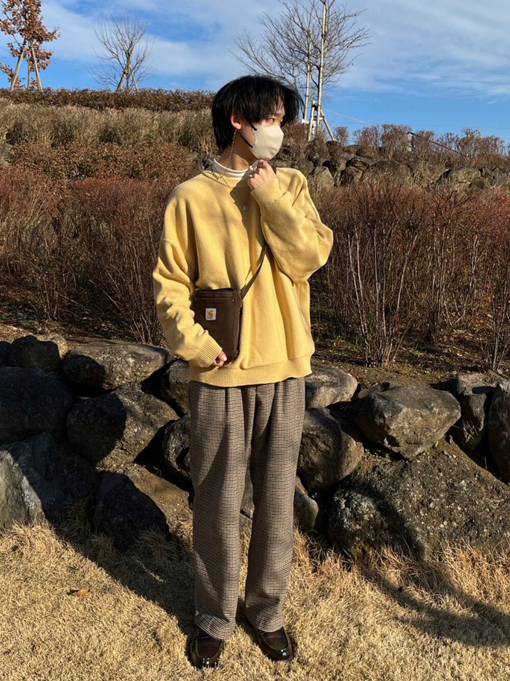 イエロー系のニット/セーター、ベージュ系のスラックス、ホワイト系のTシャツ/カットソーを着用したメンズの冬コーディネートの1枚目の写真