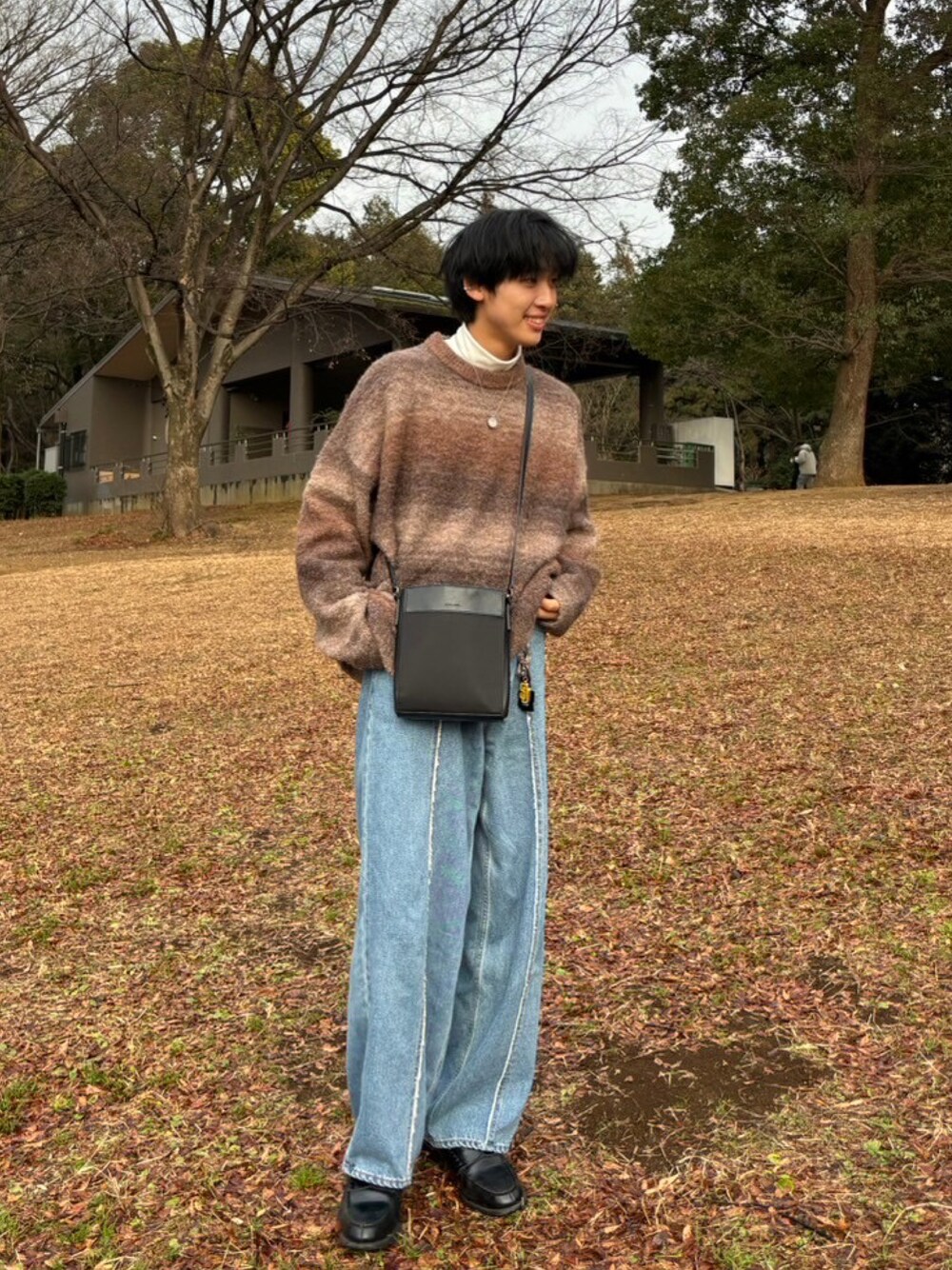 ブラウン系のニット/セーター、ブルー系のデニムパンツ、ブラック系のショルダーバッグを着用したメンズの春コーディネートの1枚目の写真