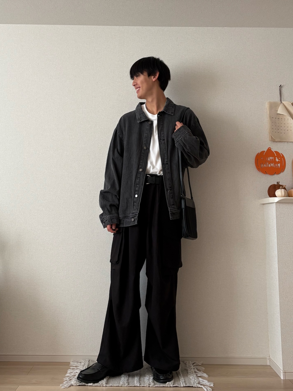 ブラック系のデニムジャケット、ブラック系のカーゴパンツ、ブラック系のショルダーバッグを着用したメンズの秋コーディネートの1枚目の写真