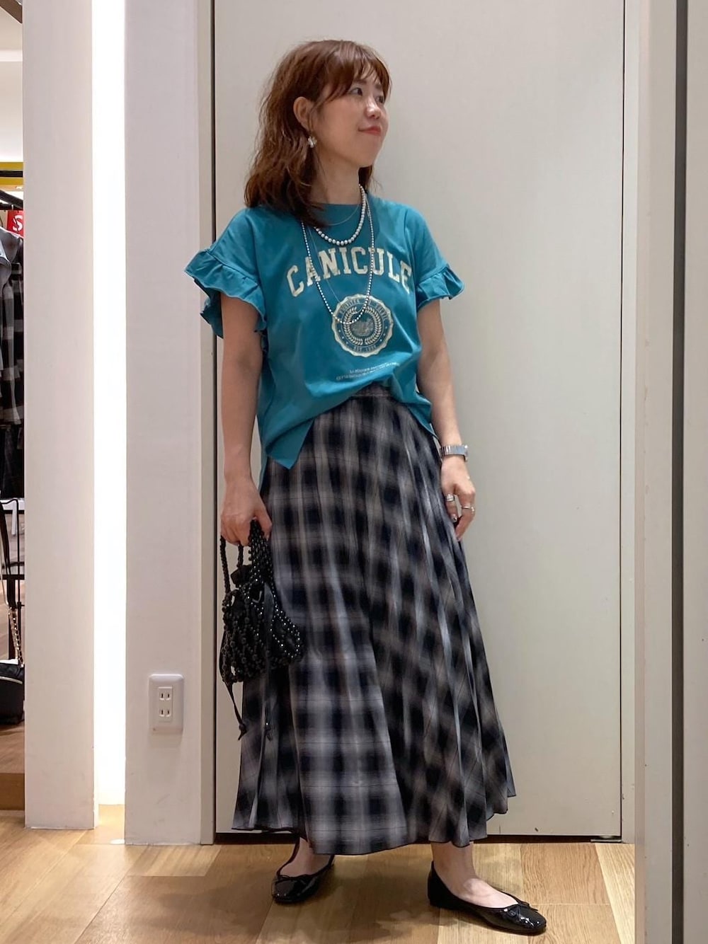 ブラック系のハンドバッグ、ブラック系のバレエシューズ、グリーン系のTシャツ/カットソーを着用したレディースの夏コーディネートの1枚目の写真