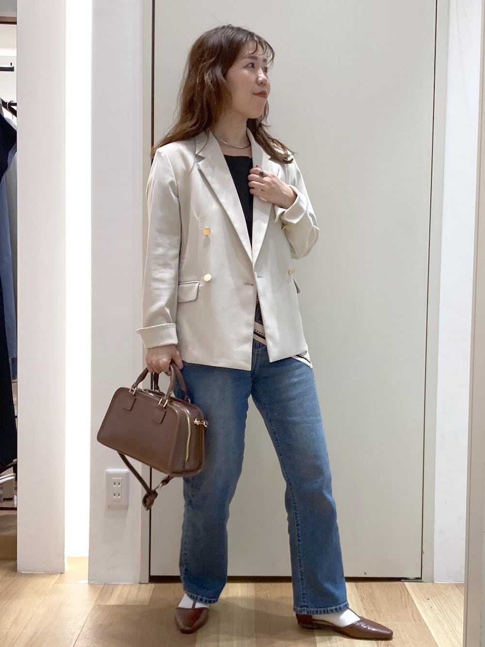 ブラウン系のボストンバッグ、ブルー系のデニムパンツ、ブラウン系のパンプスを着用したレディースの春コーディネートの1枚目の写真