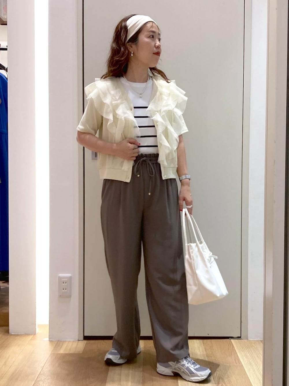 ホワイト系のトートバッグ、ホワイト系のニット/セーター、ベージュ系のTシャツ/カットソーを着用したレディースの夏コーディネートの1枚目の写真