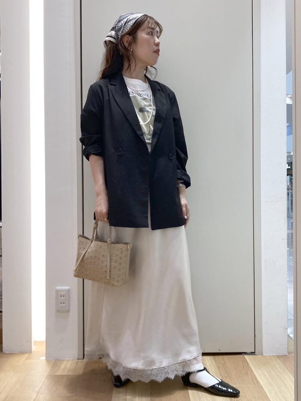 ブラック系のパンプス、ベージュ系のショルダーバッグ、ホワイト系のスカートを着用したレディースの春コーディネートの1枚目の写真