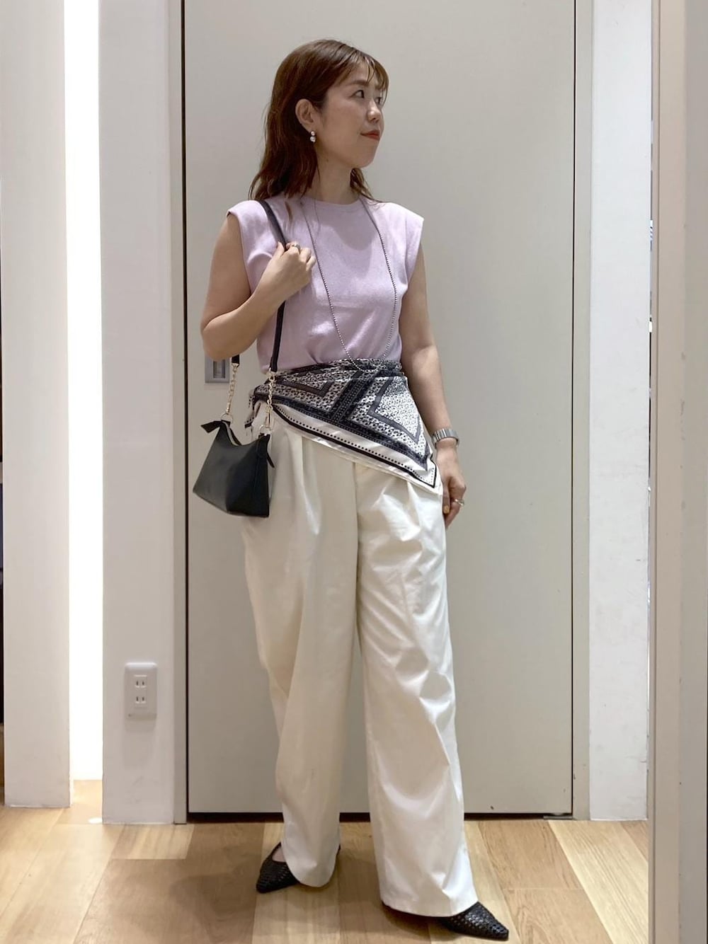 ホワイト系のチノパンツ、ブラック系のパンプス、ブラック系のショルダーバッグを着用したレディースの夏コーディネートの1枚目の写真