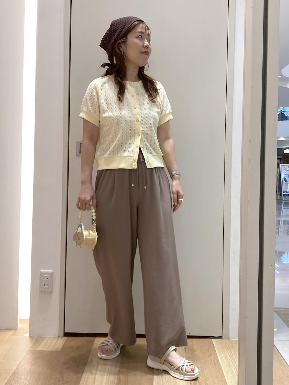 ホワイト系のサンダル、ブラウン系のその他パンツ、イエロー系のショルダーバッグを着用したレディースの夏コーディネートの1枚目の写真