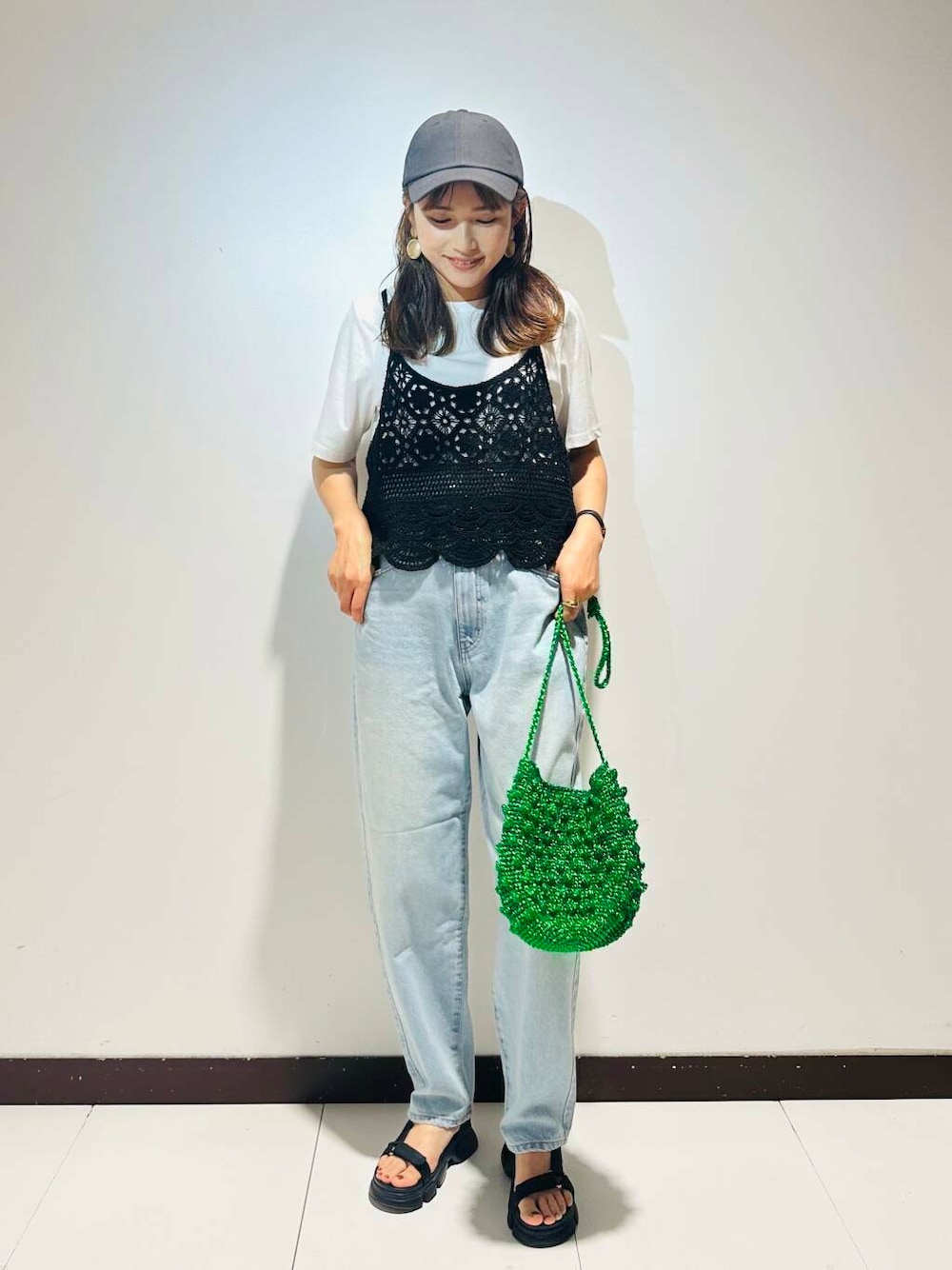 グリーン系のショルダーバッグ、ブルー系のデニムパンツ、ブラック系のキャップを着用したレディースの夏コーディネートの1枚目の写真