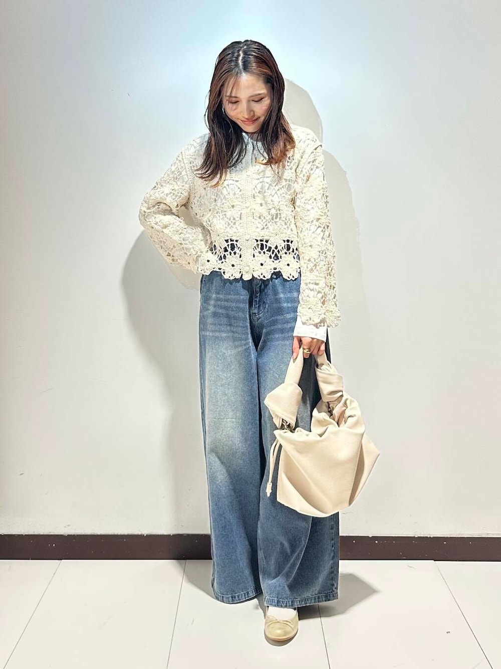 ホワイト系のハンドバッグ、ブルー系のデニムパンツ、ゴールド系のバレエシューズを着用したレディースの春コーディネートの1枚目の写真