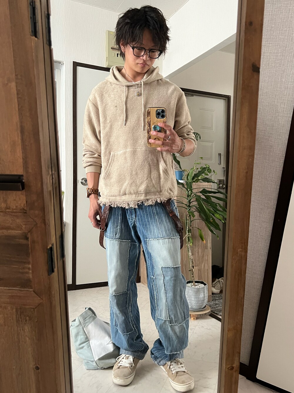 ブルー系のデニムパンツ、ベージュ系のスニーカー、ブルー系のトートバッグを着用したメンズの春コーディネートの1枚目の写真